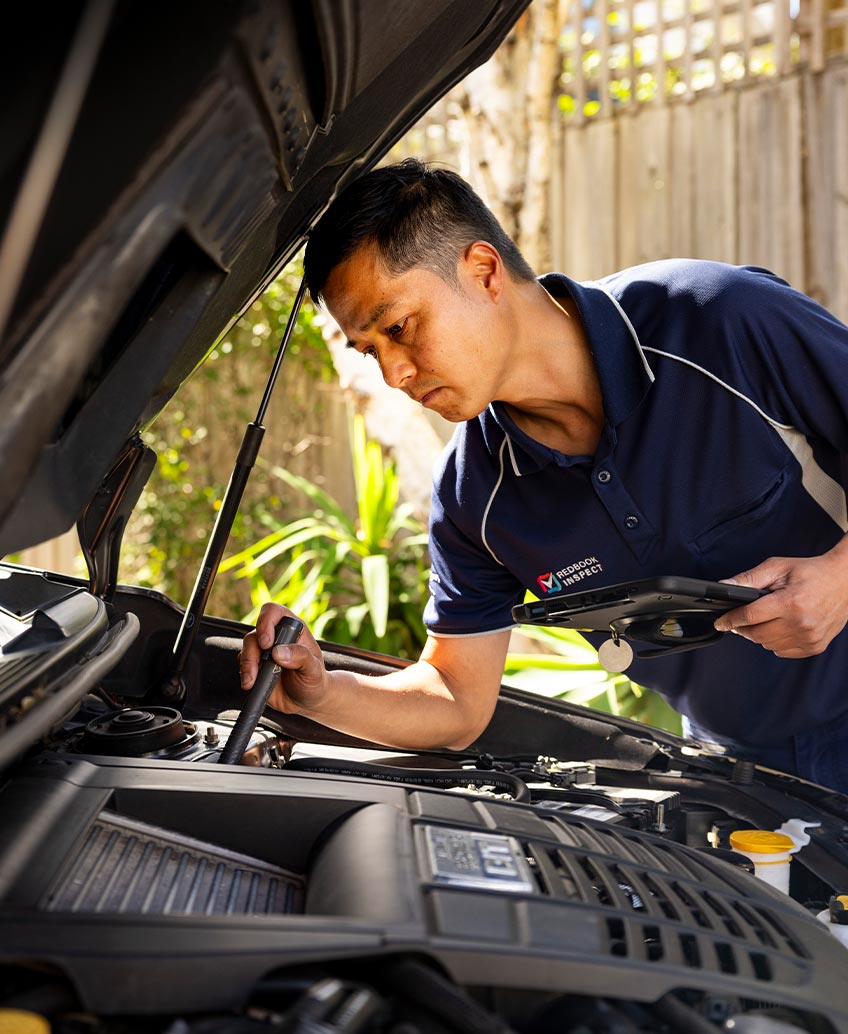 mechanic inspects used car engine